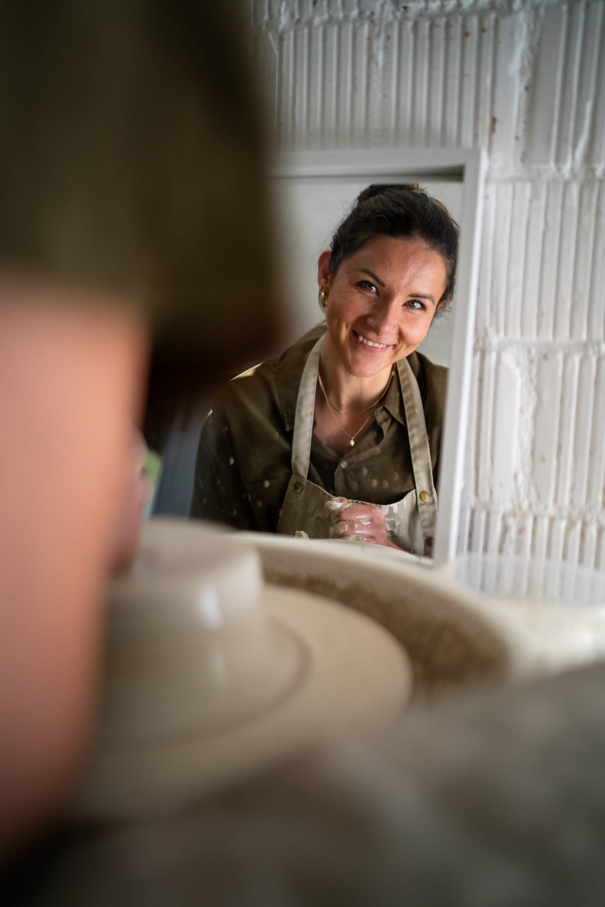 Alexandra ABättig lächelt bei der Arbeit an der Töpferscheibe in ihrem Atelier