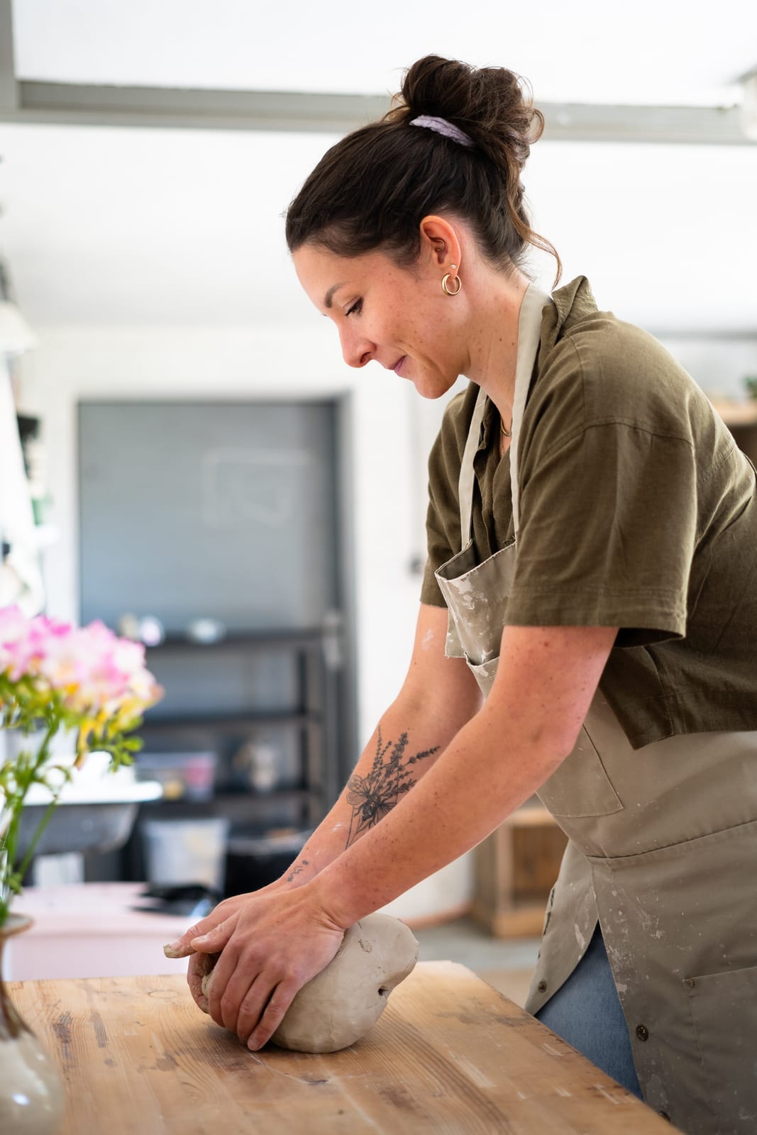 Alexandra ABättig arbeitet konzentriert an der Werkbank in ihrem Atelier, daneben ein Strauss Blumen