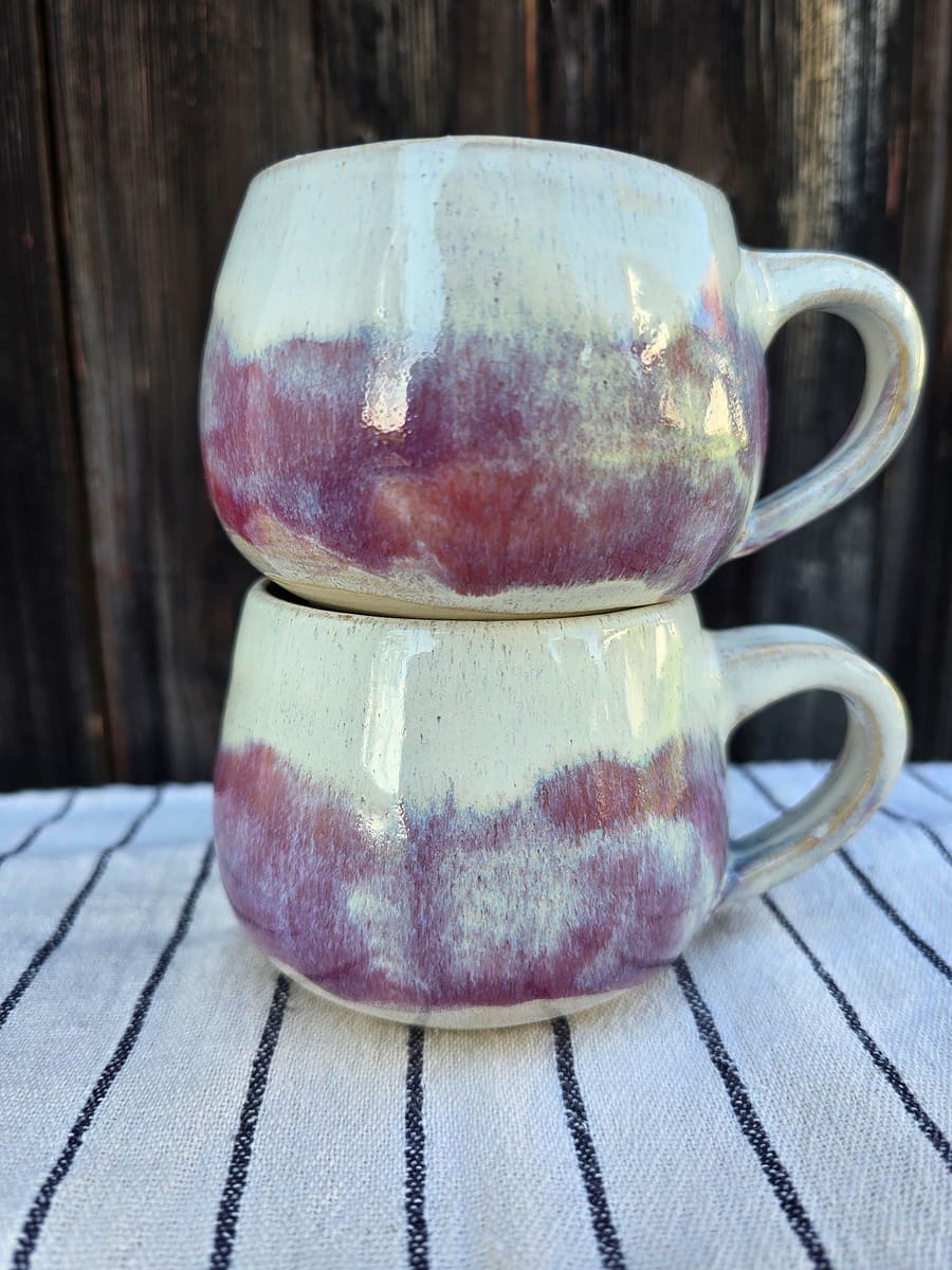 Gestapelte Becher mit beeren- und cremefarbener Glasur