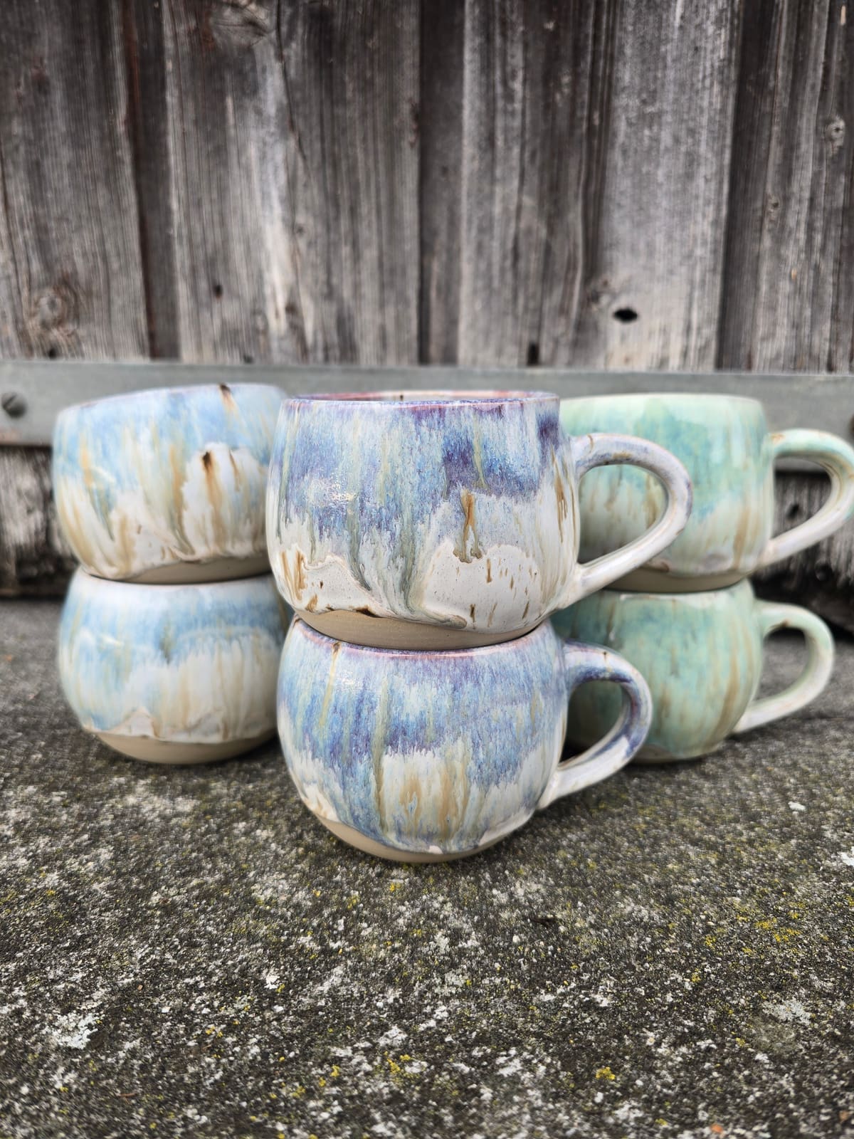 Gestapelte Becher mit blaugrüner Sprenkelglasur auf Stein