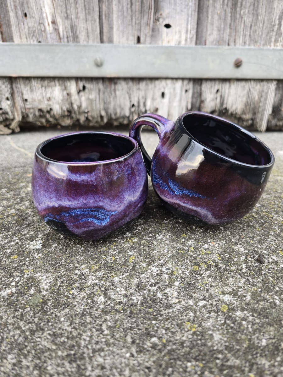 Zwei Becher mit violetter Laufglasur nebeneinander