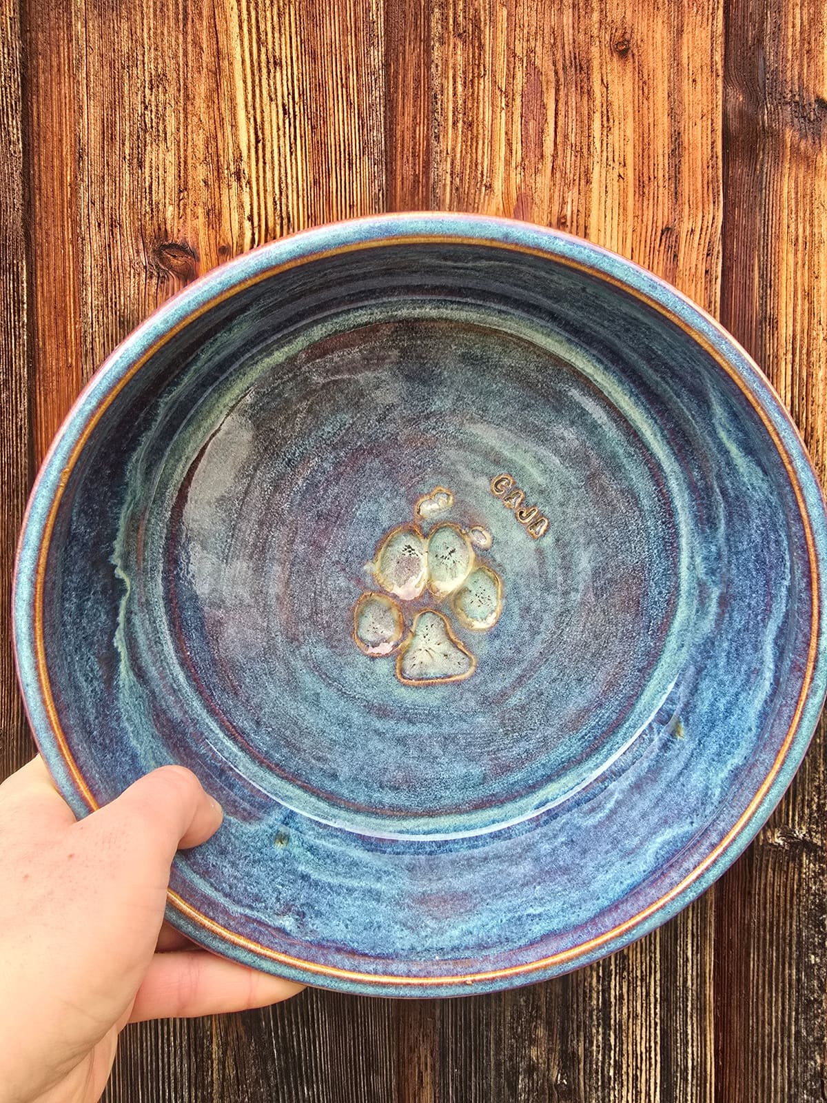 Blaue Schale mit Pfotenstempel im Spiegel, in einer Hand